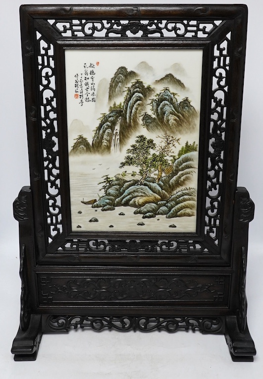 A Chinese carved table screen with a famille rose central plaque, screen 66cm high, plaque 35cm high. Condition - good